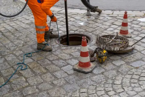 Een persoon laat iets zakken in een put.