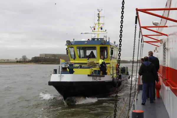 Een boot van Rijkswaterstaat vaart naast een andere boot met bemanning.